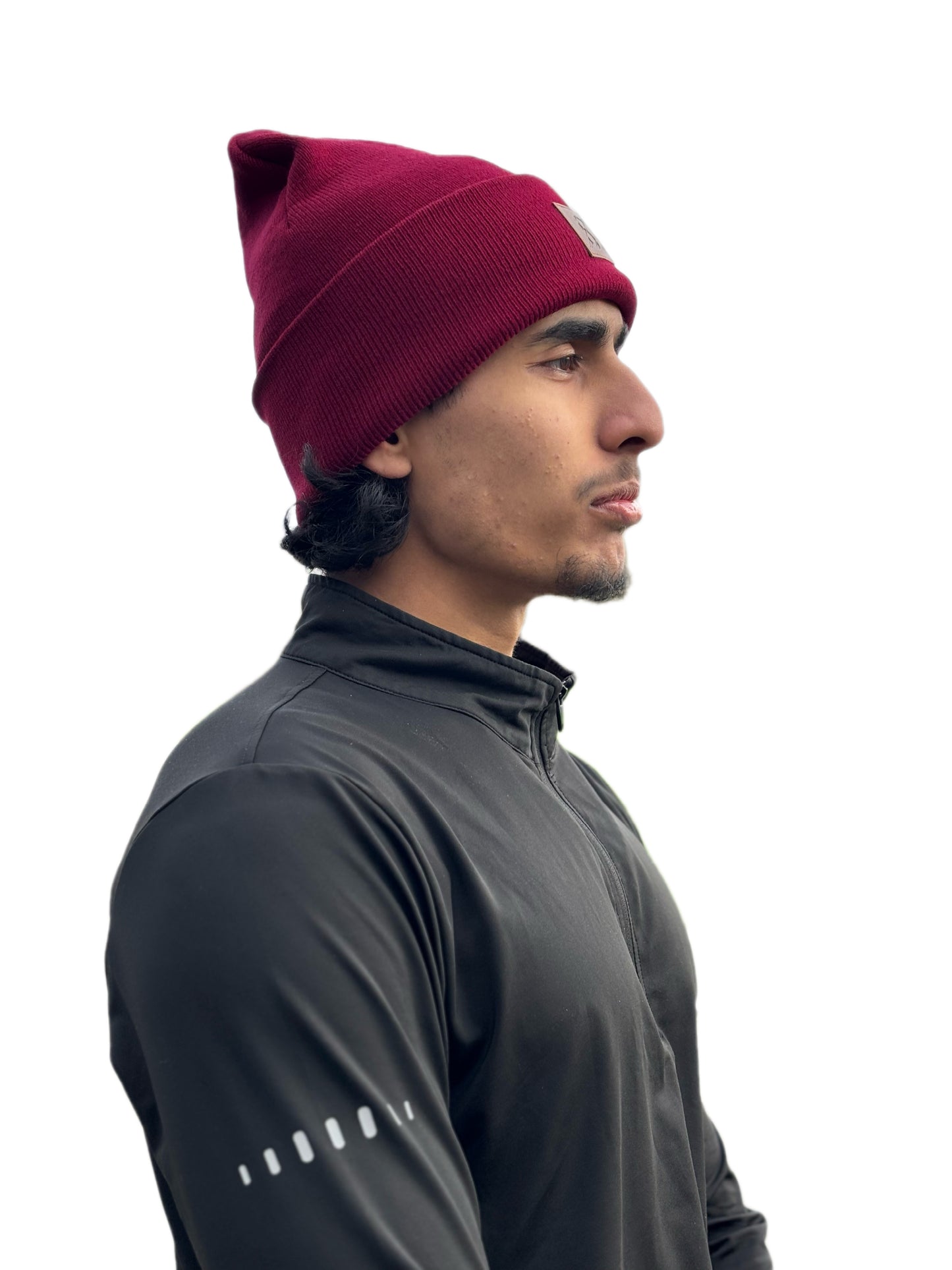 Man wearing a maroon beanie and dark gray athletic jacket on a white background